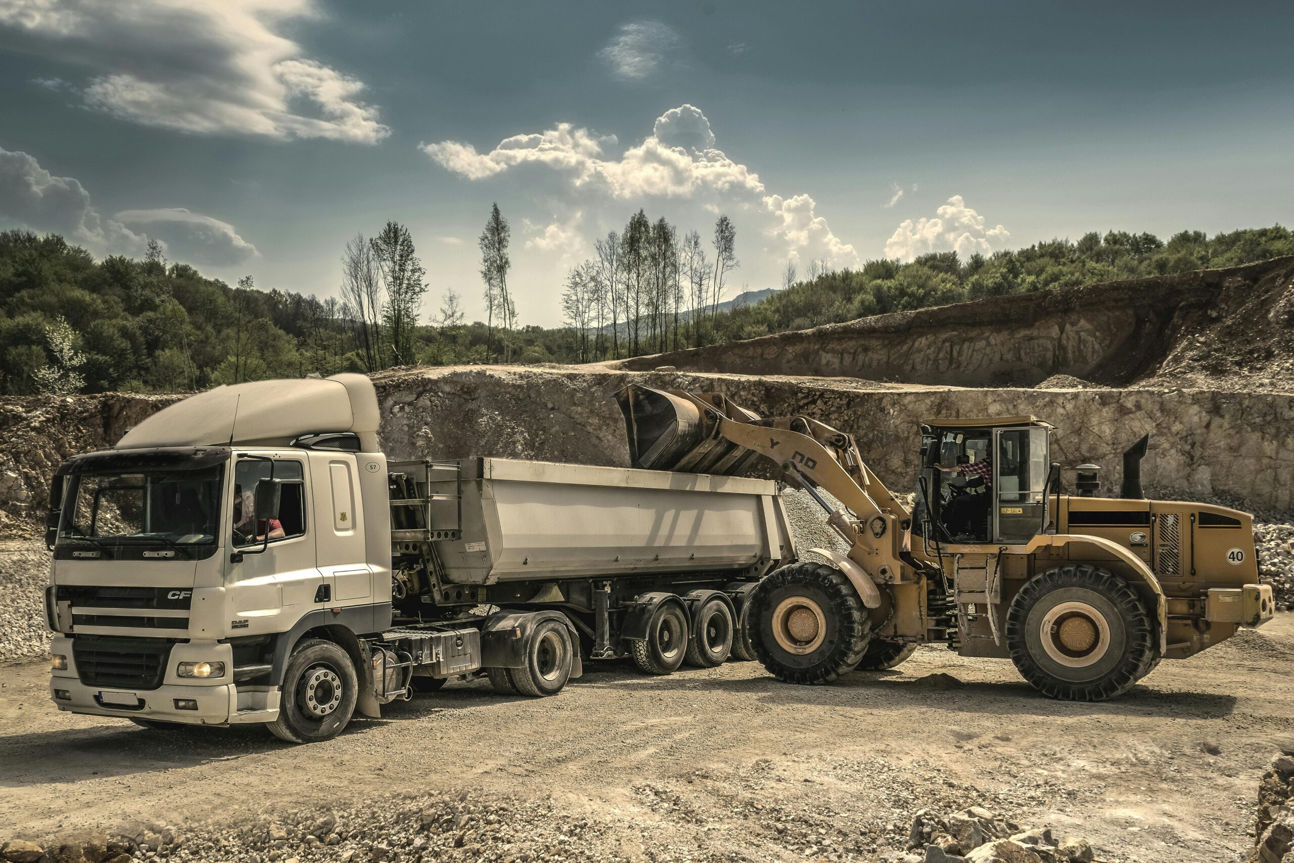 Excavator and truck working together in a quarry, showcasing industrial equipment and operations.